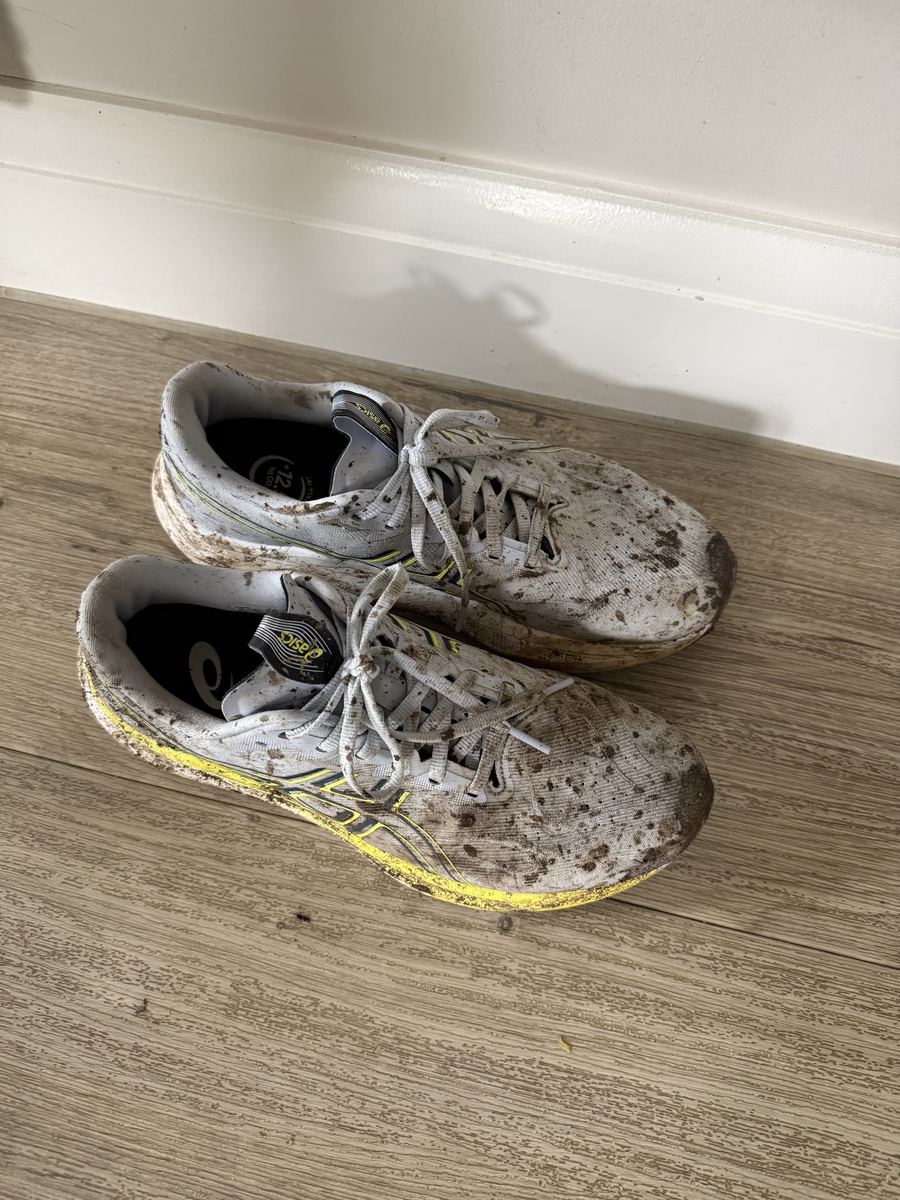 A pair of muddy running shoes back home after a wet run
