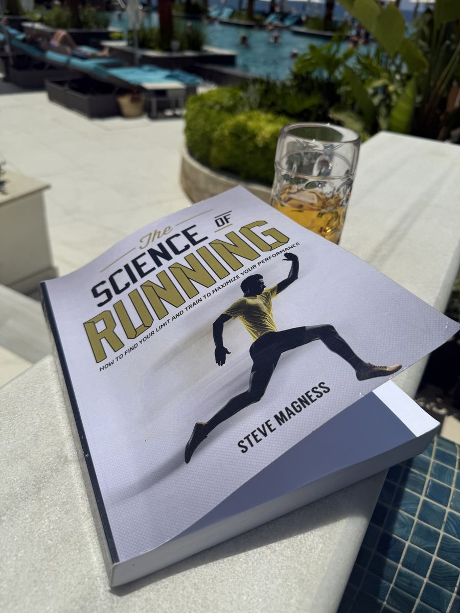 A copy of The Science of Running by Steve Magness on a table by a pool